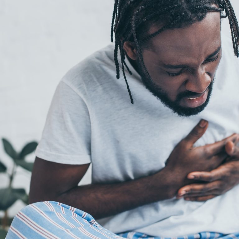 young african american man suffering from heart pain in bedroom